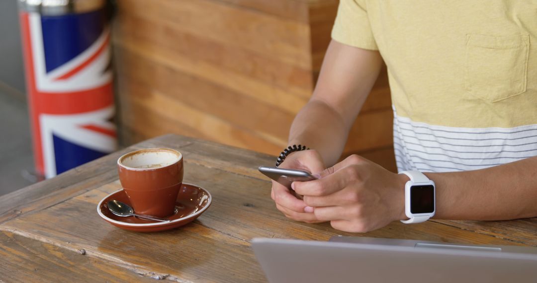 Person Using Smartphone in Cafe with Coffee and Smartwatch - Free Images, Stock Photos and Pictures on Pikwizard.com