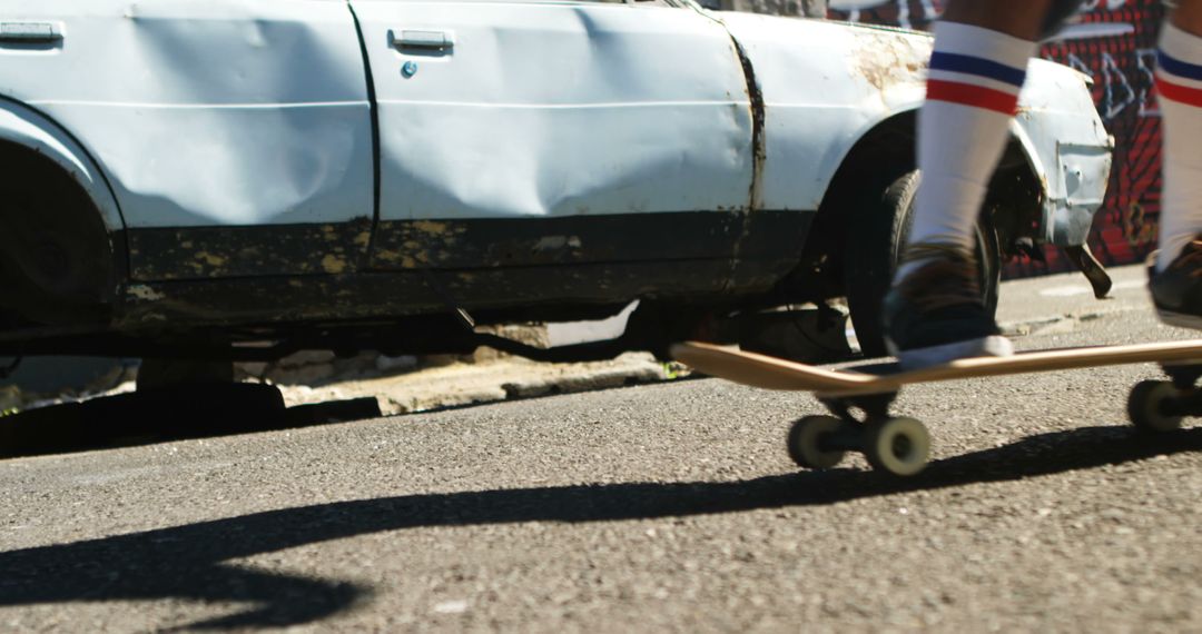 Skateboarder Passing Old Car with Damage on Urban Street - Free Images, Stock Photos and Pictures on Pikwizard.com