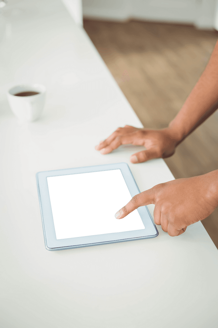 Person Touching Transparent Tablet Screen on Table with Cup