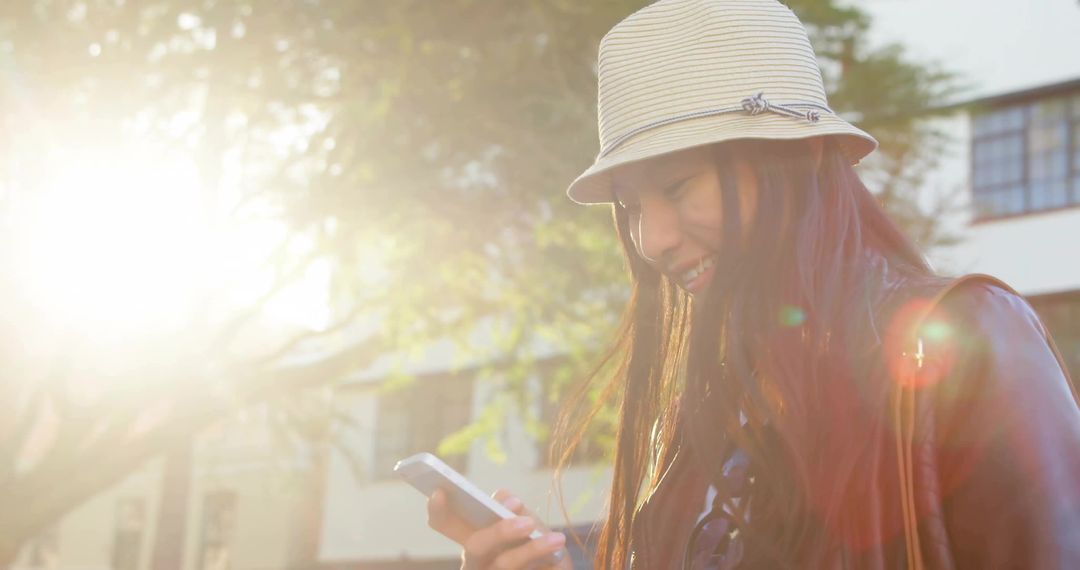 Smiling Woman Using Smartphone in Sunlit Urban Setting with Fashionable Attire