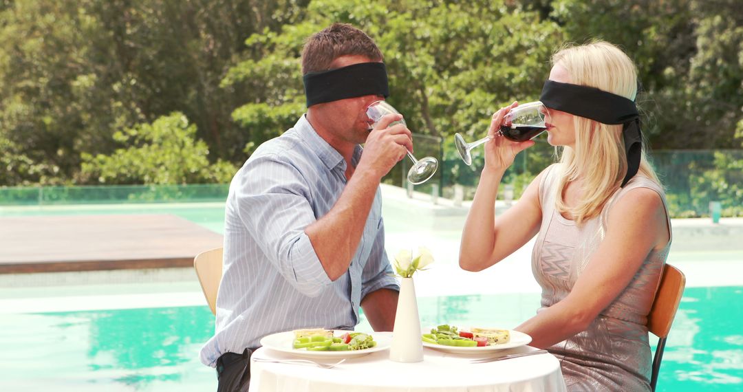 A blindfolded Caucasian couple enjoys a sensory dining experience by the poolside, with copy space - Free Images, Stock Photos and Pictures on Pikwizard.com