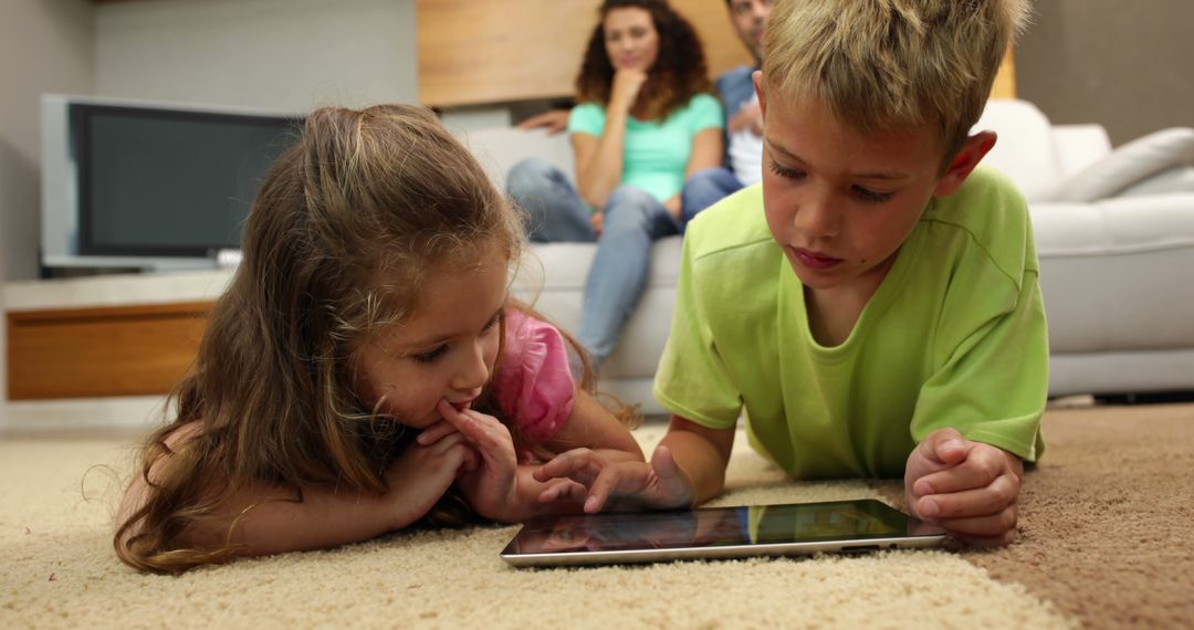 Children Playing on Tablet While Parents Sit on Couch in Background - Free Images, Stock Photos and Pictures on Pikwizard.com