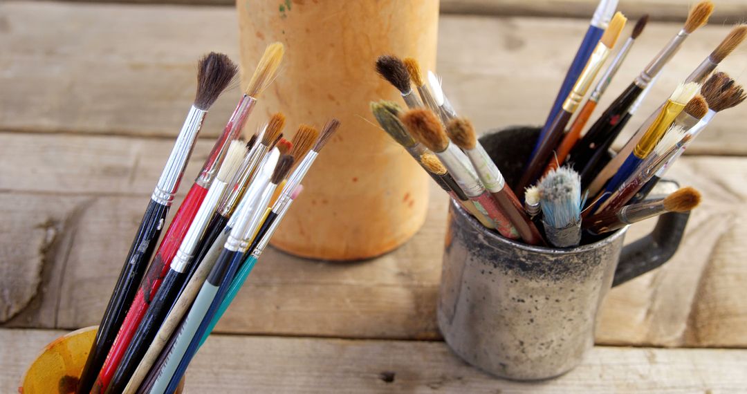 Assorted Paintbrushes in Cups on Wooden Table - Free Images, Stock Photos and Pictures on Pikwizard.com