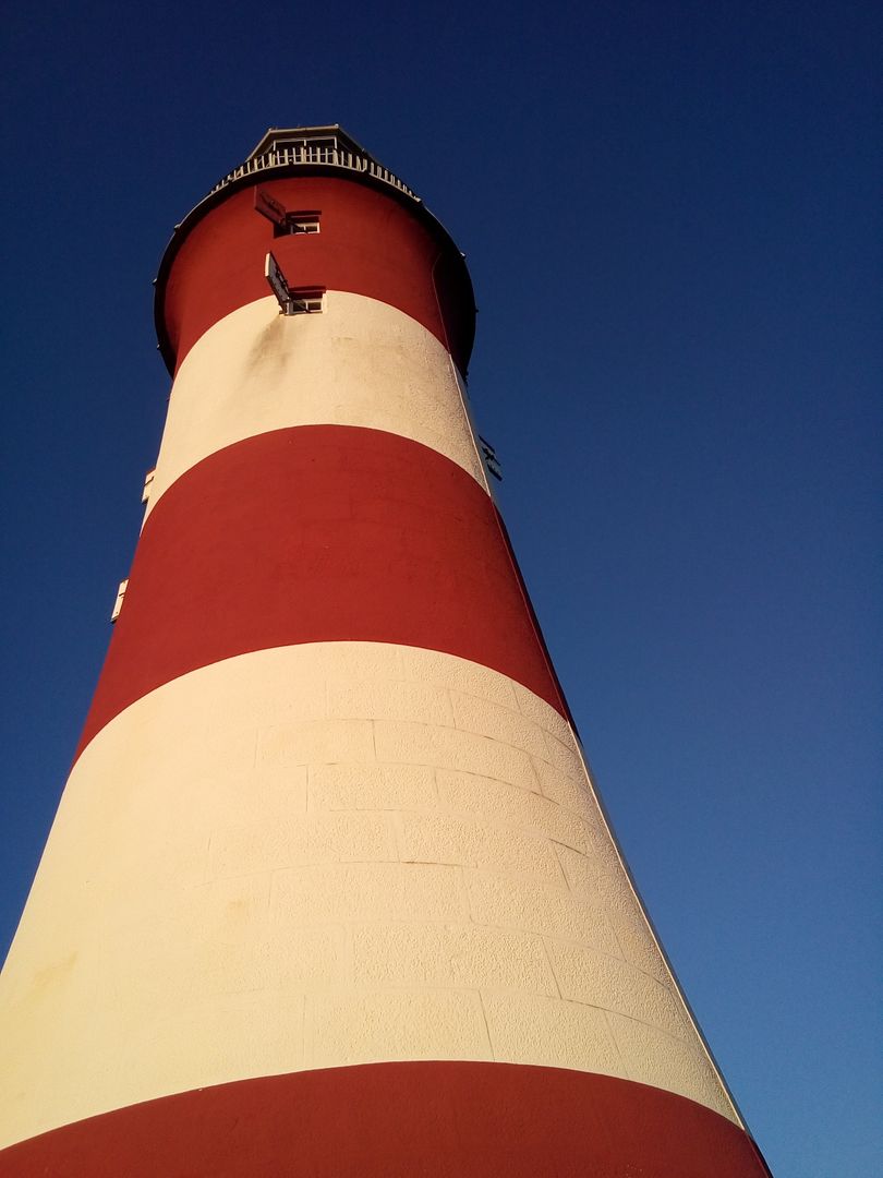 Iconic Red and White Striped Lighthouse Against Clear Blue Sky - Free Images, Stock Photos and Pictures on Pikwizard.com