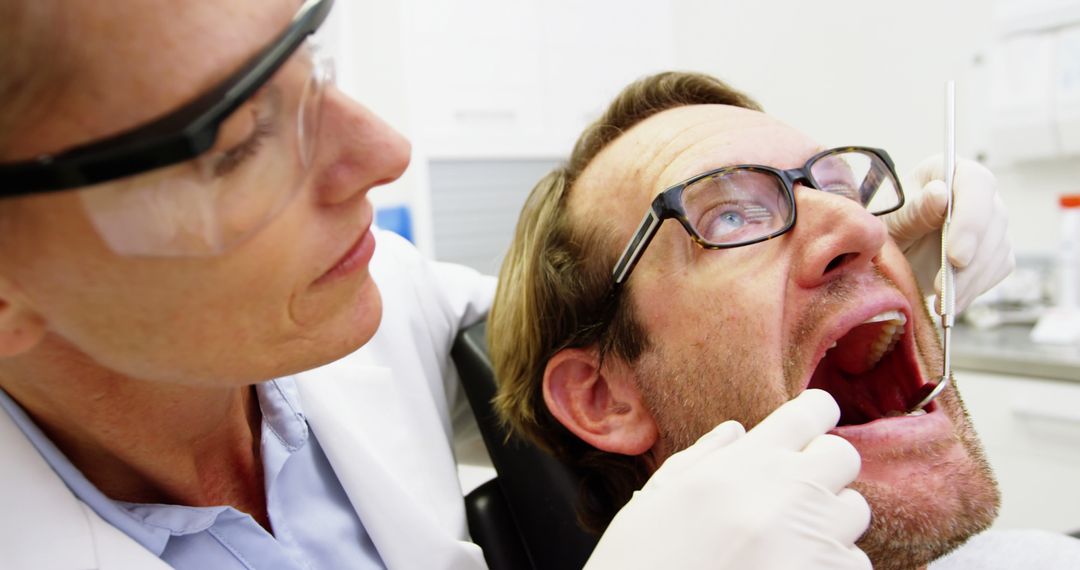 Dentist Examining Male Patient's Teeth with Dental Instruments - Free Images, Stock Photos and Pictures on Pikwizard.com