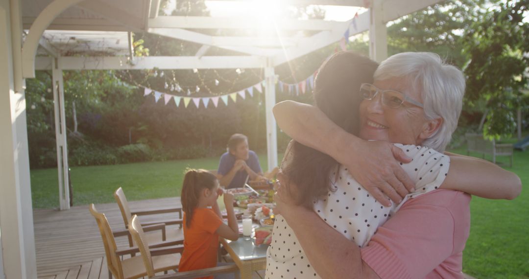 Senior Woman Embracing Family Member at Outdoor Gathering - Free Images, Stock Photos and Pictures on Pikwizard.com