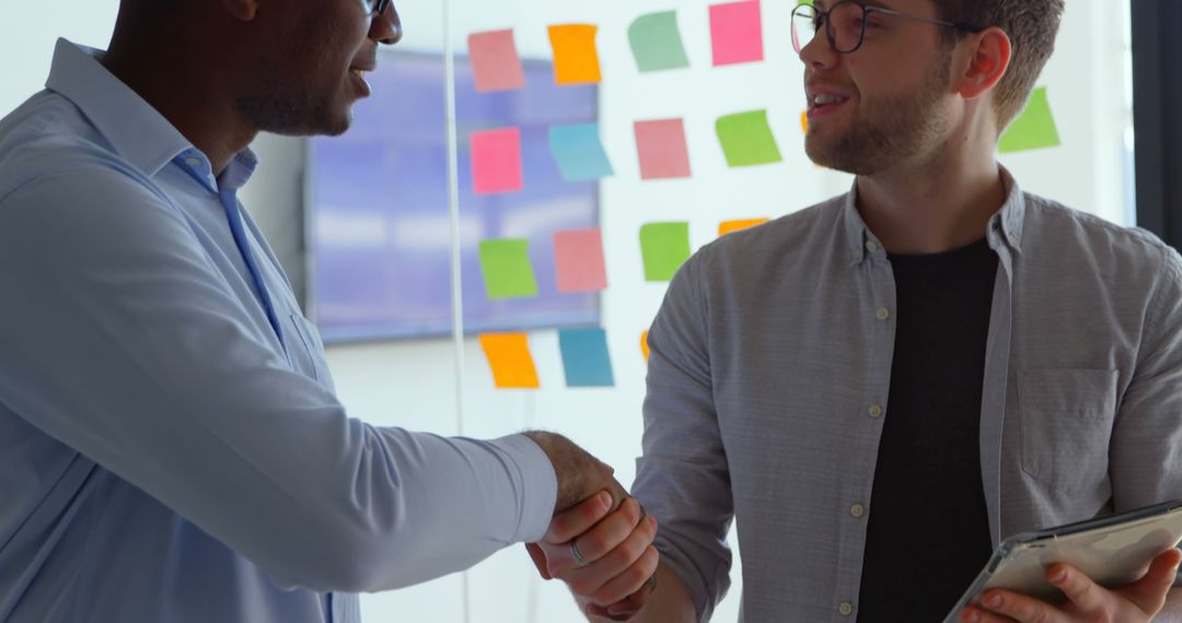 Two Multiracial Businessmen Shaking Hands in Creative Office - Free Images, Stock Photos and Pictures on Pikwizard.com