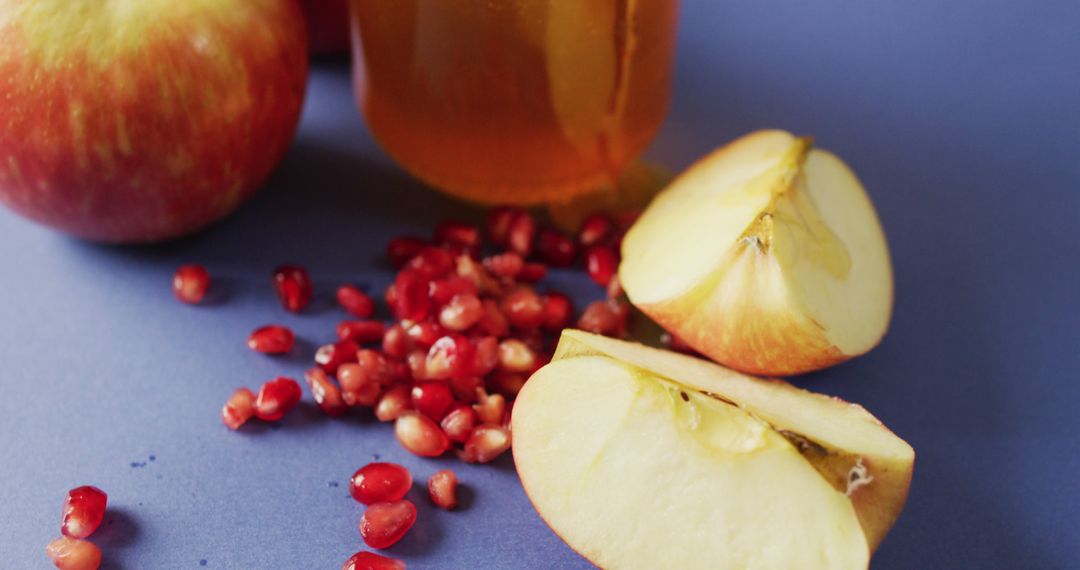 Fresh Apples and Honey with Pomegranate Seeds on Blue Backdrop