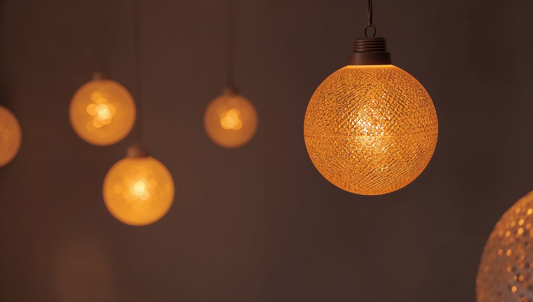 Warm glowing spherical pendant lamp hanging with textured amber glass and soft bokeh