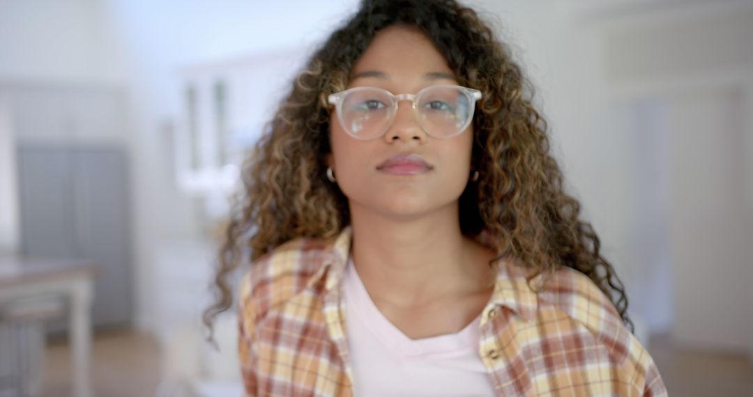 Confident Young Woman with Curly Hair and Glasses Indoors - Free Images, Stock Photos and Pictures on Pikwizard.com