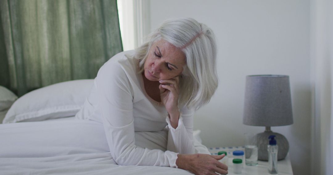 Senior Woman Sitting in Bed Feeling Unwell with Medication on Bedside Table - Free Images, Stock Photos and Pictures on Pikwizard.com