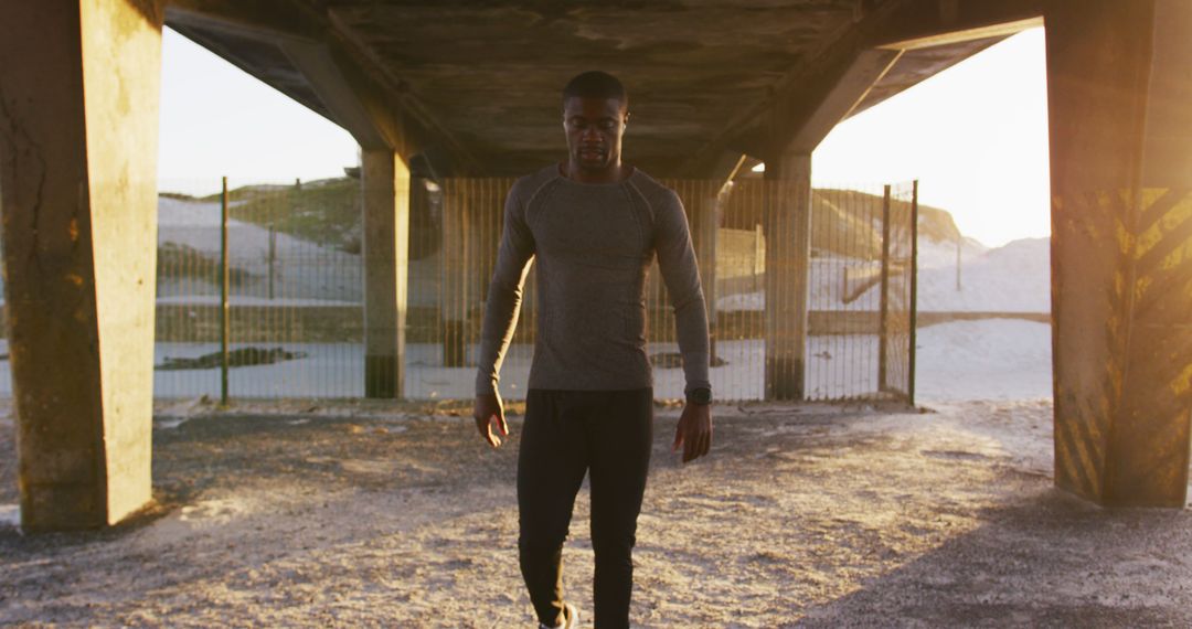 Athletic Man Walking Under Bridge During Sunset - Free Images, Stock Photos and Pictures on Pikwizard.com