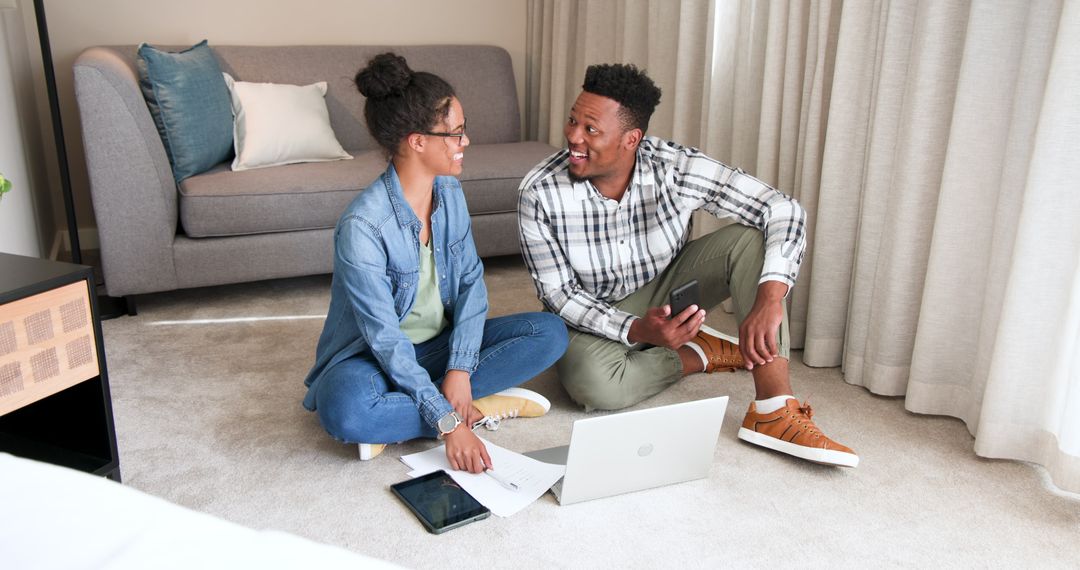 Happy Couple Discussing Finances While Using Laptop at Home