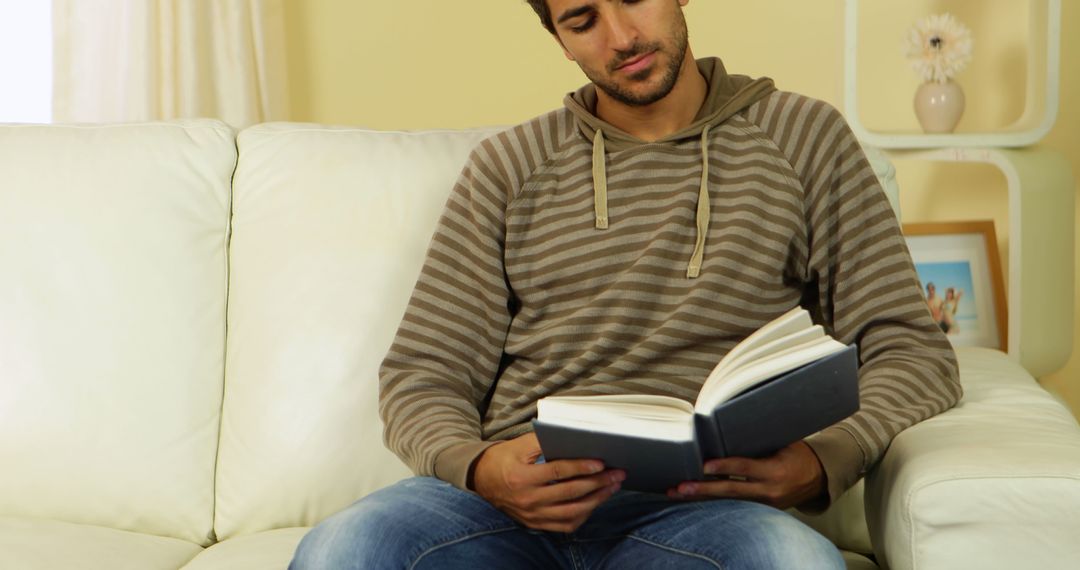 Young Man Reading Book on Couch in Comfortable Home Setting - Free Images, Stock Photos and Pictures on Pikwizard.com