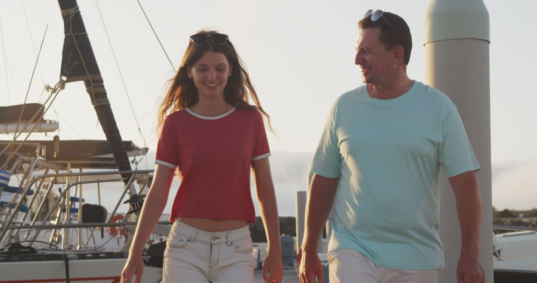 Father and daughter enjoying walk on marina at sunset - Free Images, Stock Photos and Pictures on Pikwizard.com