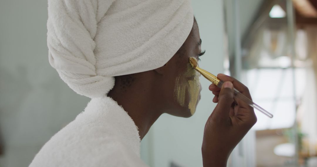 Portrait of african american attractive woman applying face mask in bathroom - Free Images, Stock Photos and Pictures on Pikwizard.com