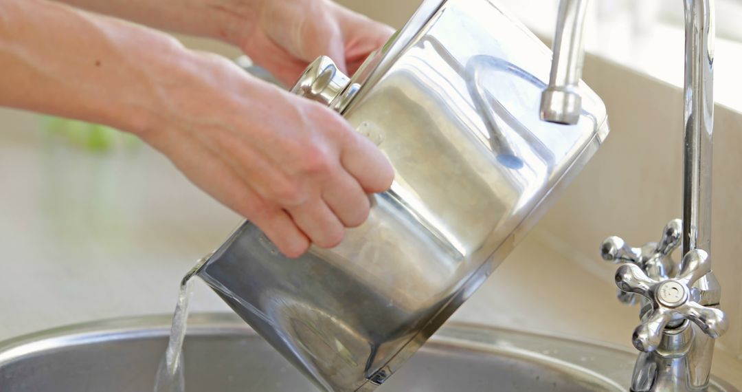 Person rinsing stainless steel pot in kitchen sink - Free Images, Stock Photos and Pictures on Pikwizard.com