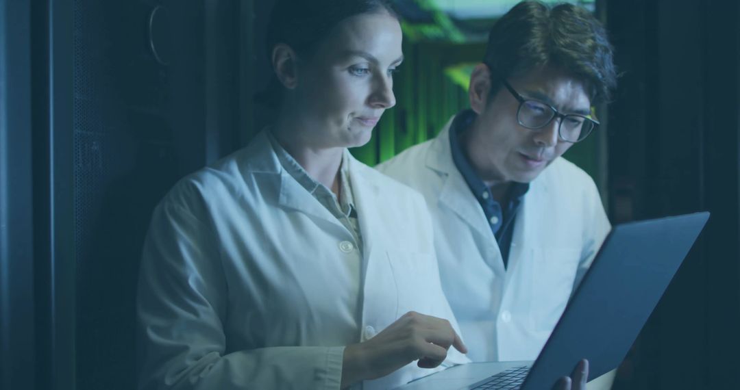 Technicians Collaborate in Data Center with Laptop and LED Light