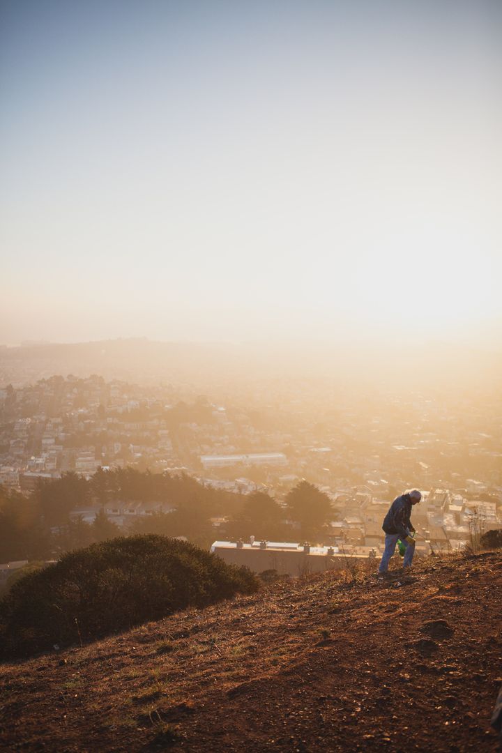 Hiker Climbing Hill Overlooking City at Sunrise - Free Images, Stock Photos and Pictures on Pikwizard.com