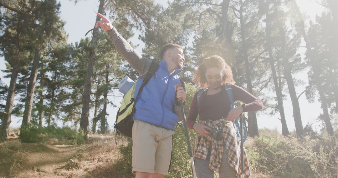 Joyful Couple Hiking in Sunny Forest with Backpacks