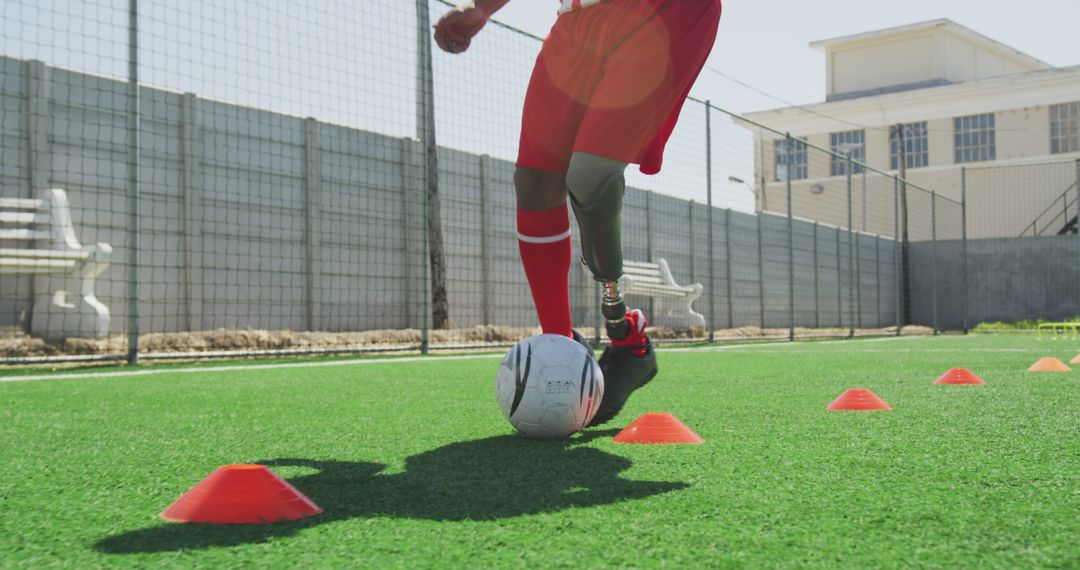 Athlete with prosthetic leg dribbling soccer ball through cones - Free Images, Stock Photos and Pictures on Pikwizard.com