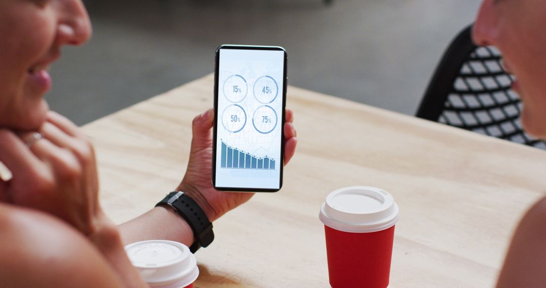 Coworkers Analyzing Data on Smartphone Over Coffee