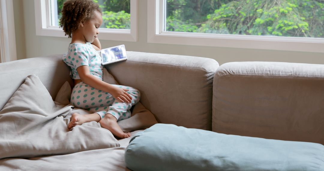 Little Girl Watching Tablet on Couch in Cozy Wohnzimmer - Free Images, Stock Photos and Pictures on Pikwizard.com