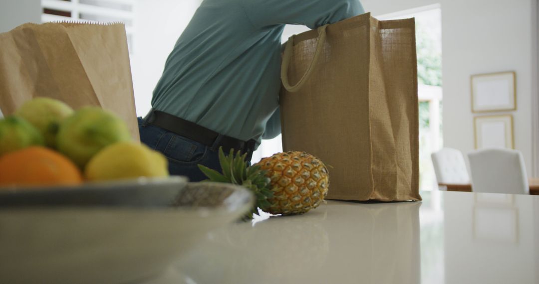 Person Unpacking Groceries from Reusable Bag in Modern Kitchen - Free Images, Stock Photos and Pictures on Pikwizard.com