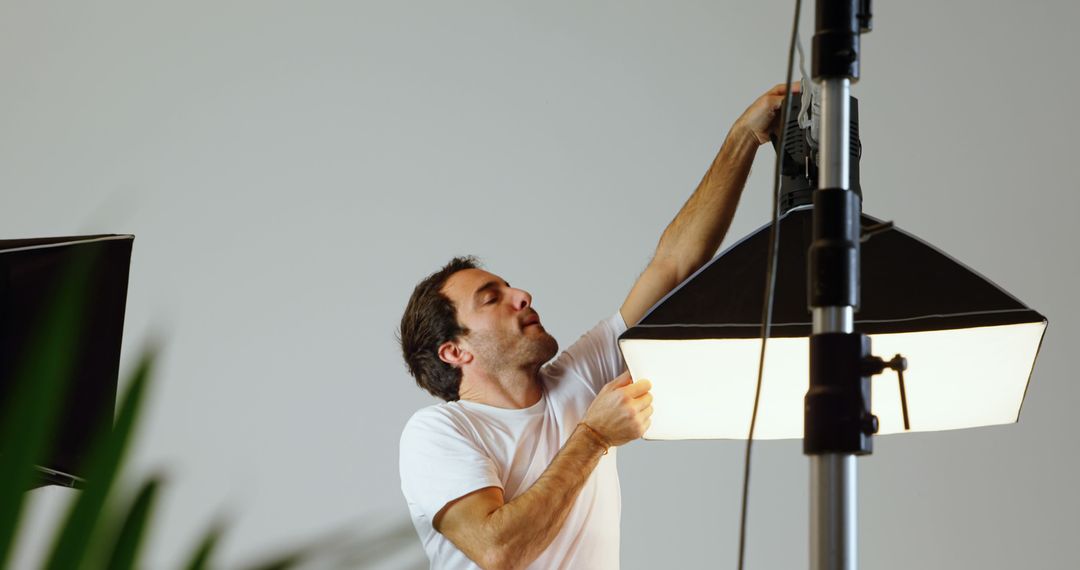 A skilled man sets up lighting in a studio, possibly for a photoshoot or film. - Free Images, Stock Photos and Pictures on Pikwizard.com