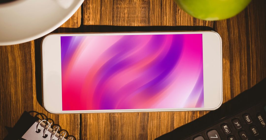 Smartphone Displaying Abstract Pink Shapes on Wooden Desk