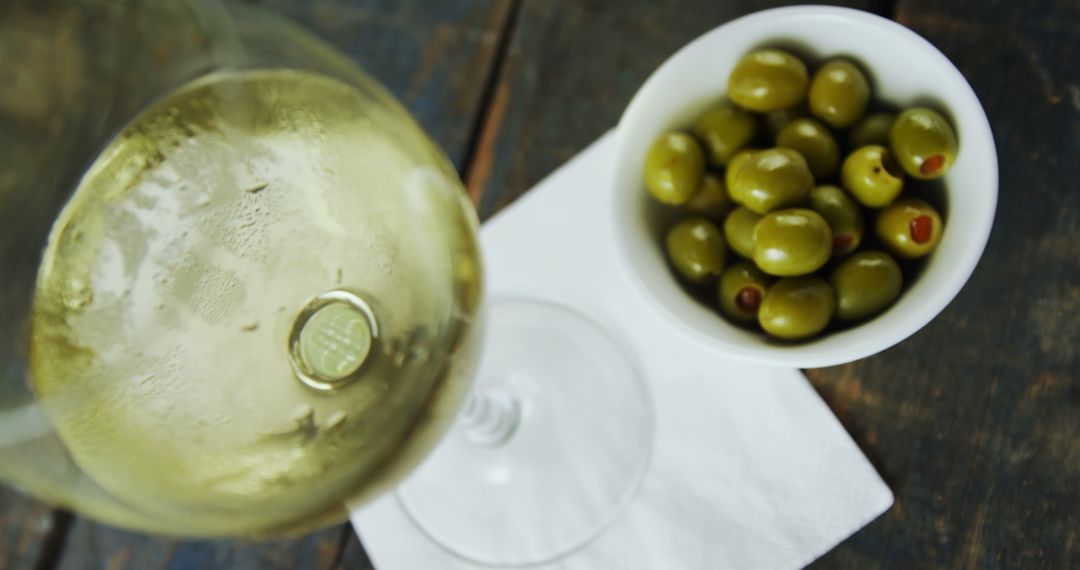 Chilled White Wine Glass with Green Olives in Bowl on Rustic Wood Table - Free Images, Stock Photos and Pictures on Pikwizard.com