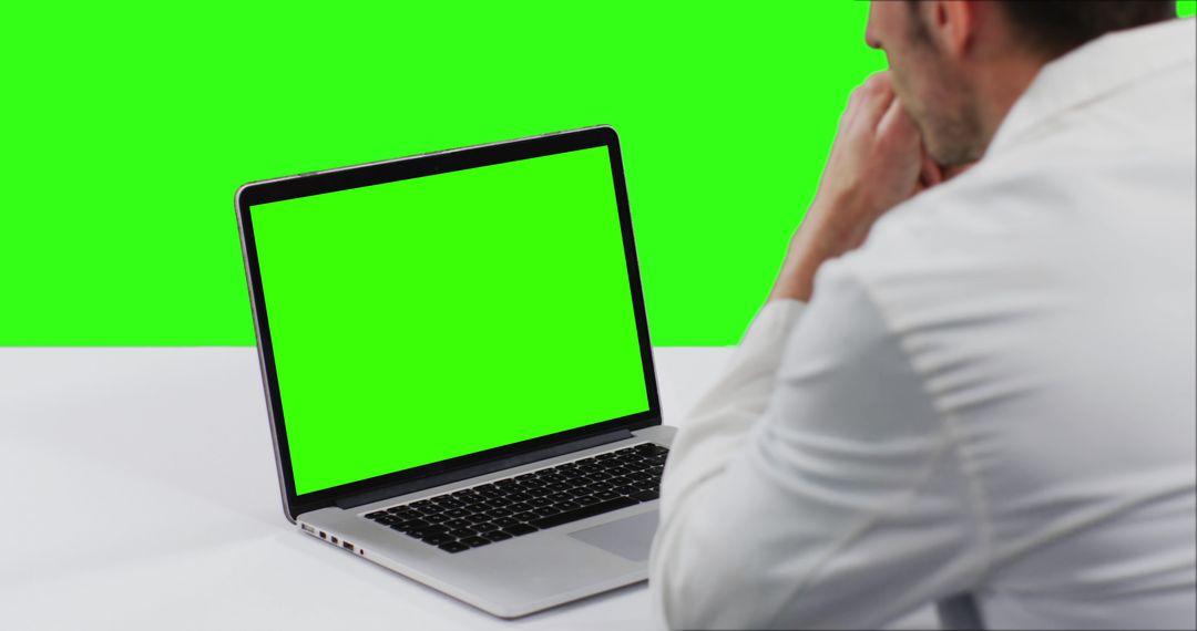 Man Looking at Laptop Screen with Green Screen Display - Free Images, Stock Photos and Pictures on Pikwizard.com