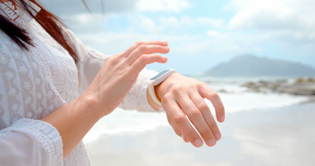 Woman Using Smartwatch On Beach On Sunny Day - Free Images, Stock Photos and Pictures on Pikwizard.com