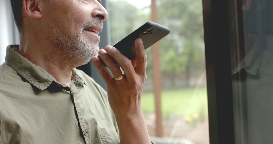 Mature Man Using Voice Assistant on Smartphone near Window - Free Images, Stock Photos and Pictures on Pikwizard.com