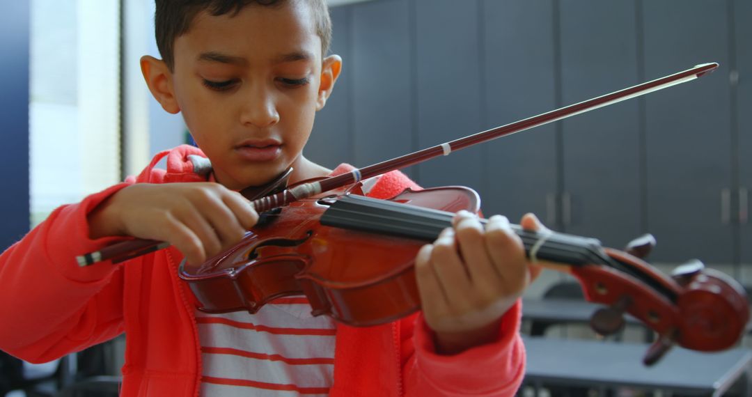 Young Boy Concentrating on Violin Practice in Classroom