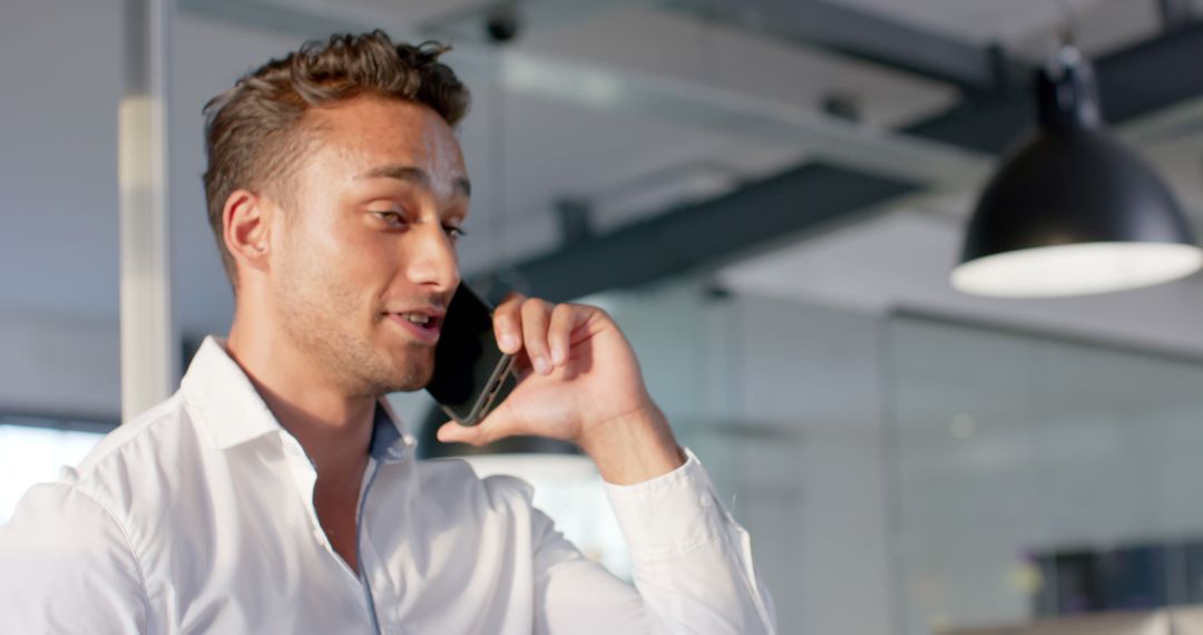 Confident businessman in white shirt talking on phone in modern office - Free Images, Stock Photos and Pictures on Pikwizard.com