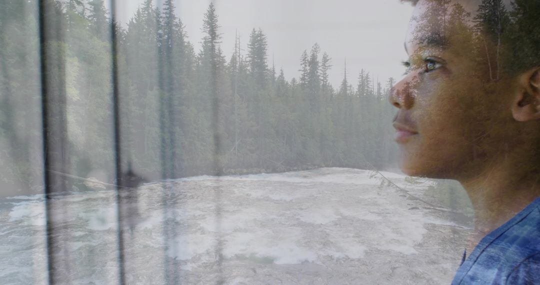 Boy gazing through window at rushing river double exposure contemplative forest portrait