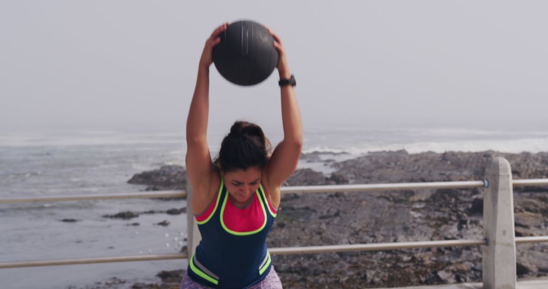 Determined Woman Working Out with Medicine Ball Outdoors by Ocean - Free Images, Stock Photos and Pictures on Pikwizard.com