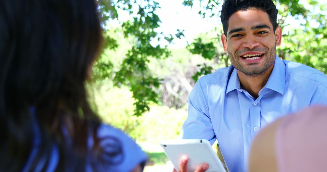 Smiling businessman holding tablet in outdoor meeting - Free Images, Stock Photos and Pictures on Pikwizard.com