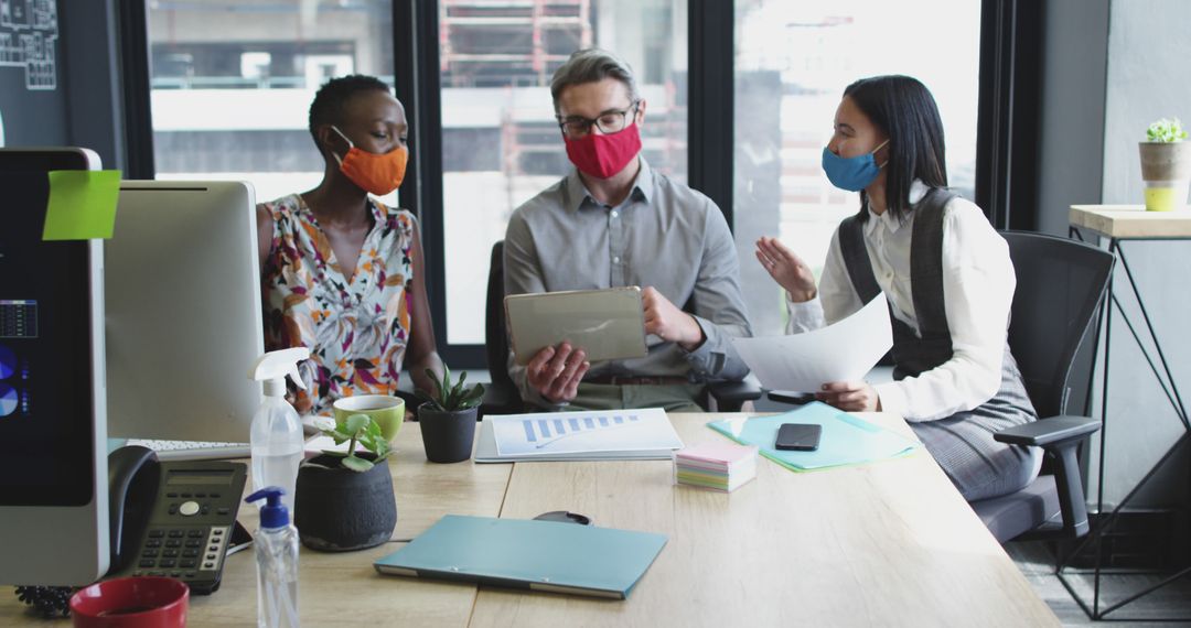 Diverse Business Team Collaborating with Tablets and Masks in Modern Office