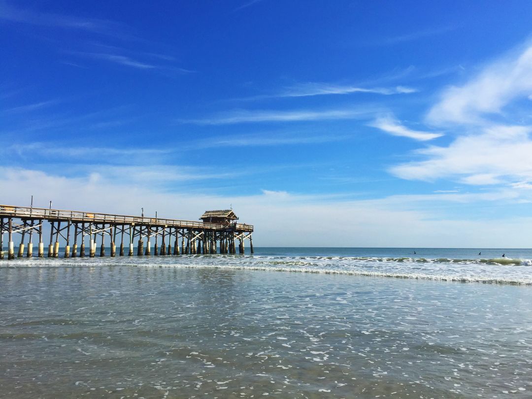 Peaceful Beach with Wooden Pier Extending into Ocean