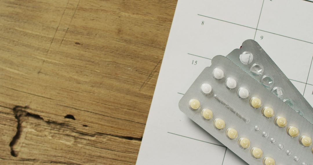 Birth control pills on wooden table with calendar in background - Free Images, Stock Photos and Pictures on Pikwizard.com