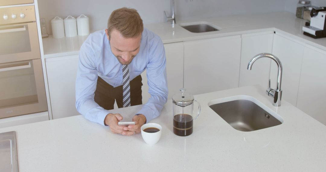 Businessman in Modern Kitchen Checking Smartphone with Coffee - Free Images, Stock Photos and Pictures on Pikwizard.com