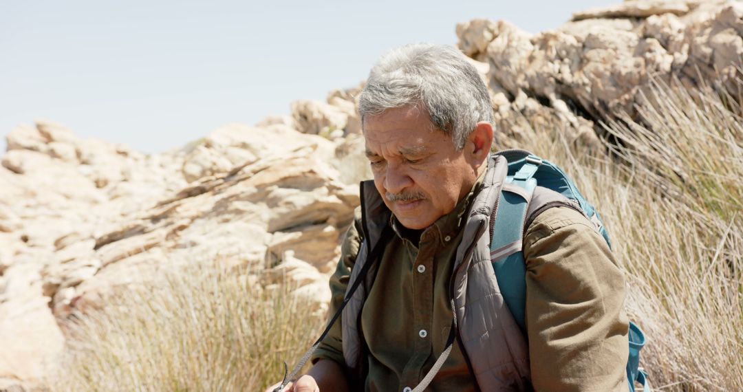 Senior Man Enhancing Outdoor Adventures Reading Map in Rocky Desert - Free Images, Stock Photos and Pictures on Pikwizard.com