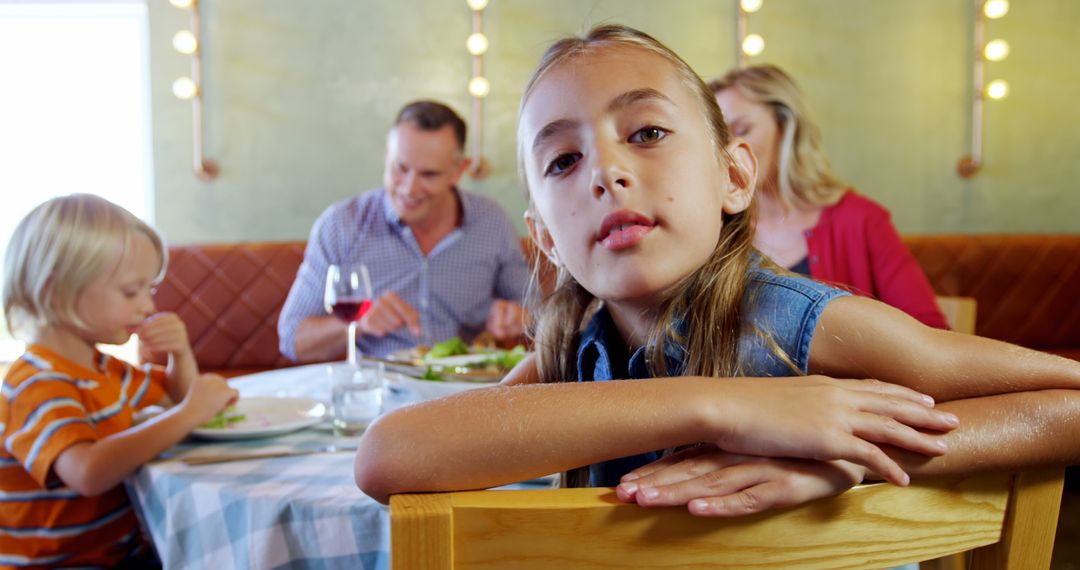 Family Enjoying Meal at Restaurant with Thoughtful Girl in Foreground - Free Images, Stock Photos and Pictures on Pikwizard.com