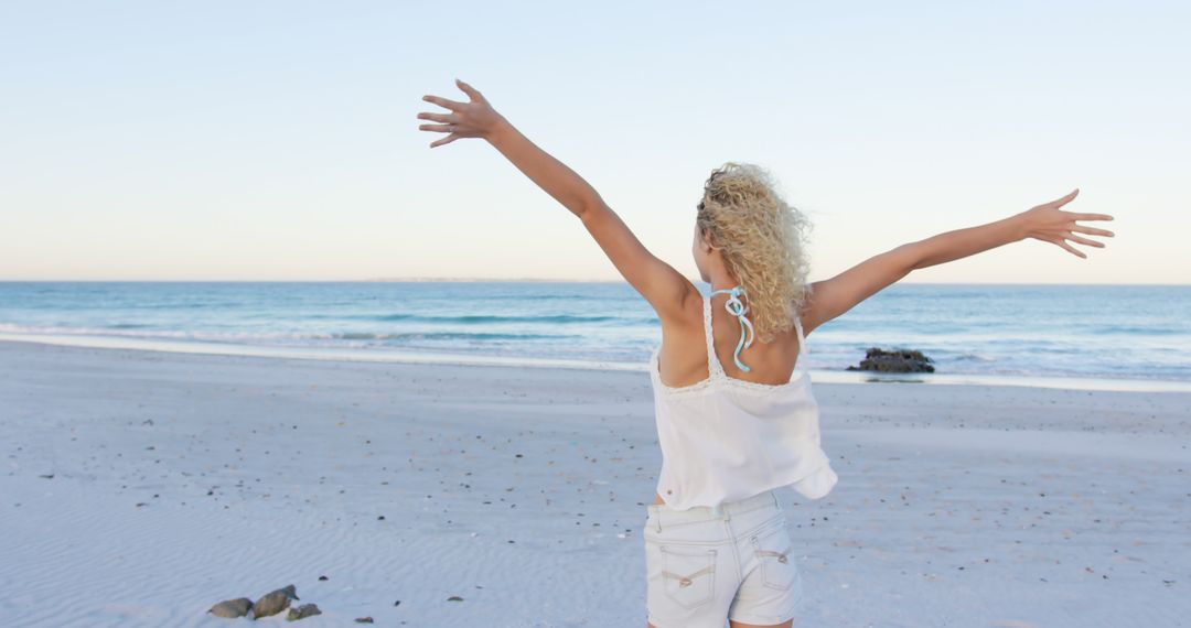 Joyful Woman on Beach with Arms Outstretched at Sunrise - Free Images, Stock Photos and Pictures on Pikwizard.com