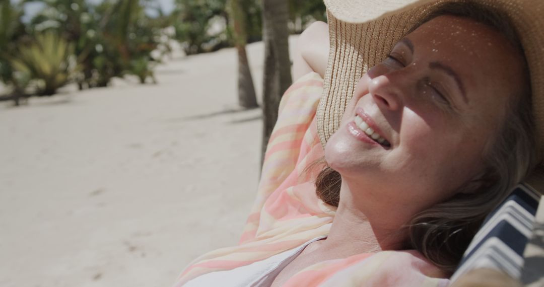 Senior Woman Relaxing on a Sunny Beach in Hat - Free Images, Stock Photos and Pictures on Pikwizard.com