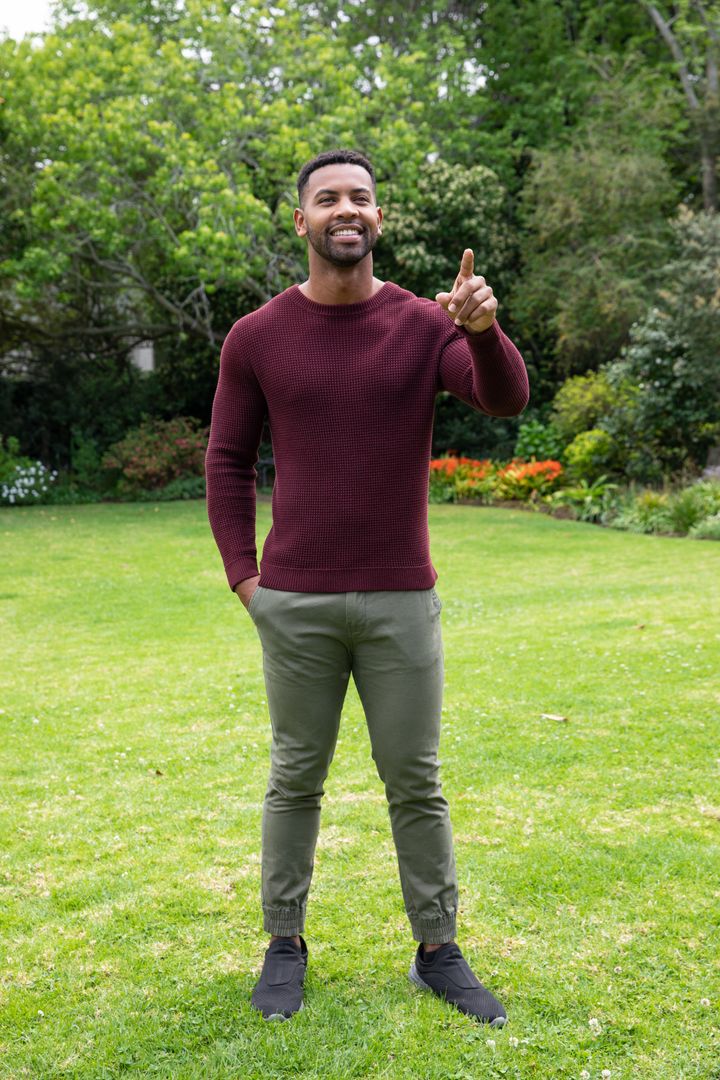 Man Enjoying Nature in Garden Pointing Towards Flower Bed