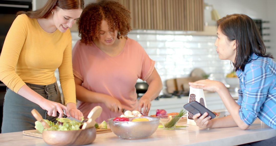Diverse Women Using Smartphone for Cooking Recipe in Kitchen