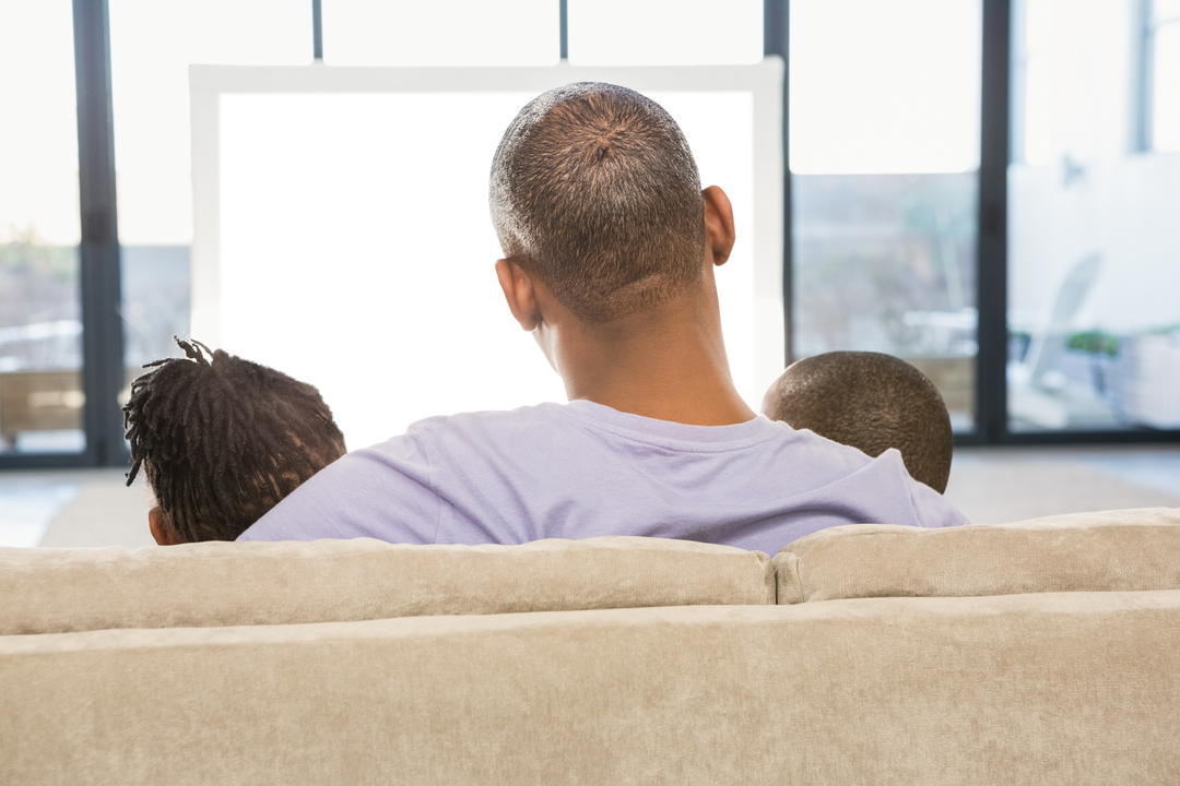 Transparent family sitting on sofa from behind watching television together at home - Download Free Stock Images Pikwizard.com